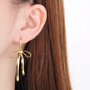 Close-up of 18K gold-plated bow earrings with inlaid zircons on a female model