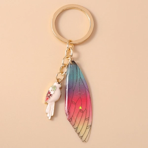 Detail of luxury gold keychain with pink bird and gradient butterfly wing charms