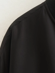 Detailed view of the ribbed neckline and smooth shoulder seams on a black bomber jacket