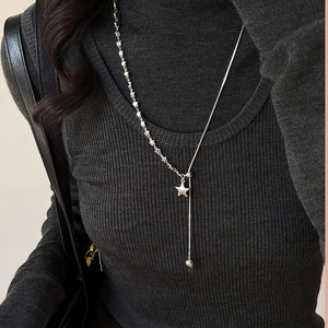 Detailed close-up of a silver asymmetric star pendant on a long Y-shaped snake chain necklace