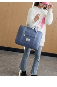 Close-up of a large grey-blue nylon travel bag featuring a front pocket and sturdy handles