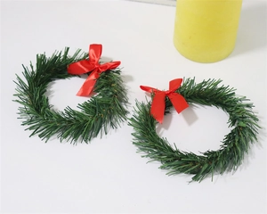 Pair of green mini Christmas wreaths with red bows and pine needles for candle rings