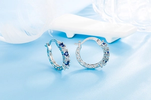 Close-up of S925 sterling silver hoop earrings with round blue and white gemstones