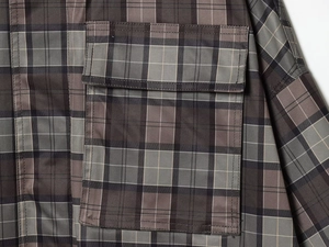 Macro shot of checkered trench coat featuring utility flap pockets and precise stitching