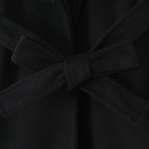 Close-up of a stylish bow knot tied on the waist belt of a black wool blend coat