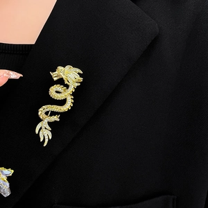 Detail of gold-plated dragon brooch with sparkling crystals on a black suit blazer