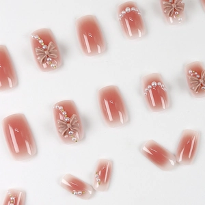 Pink blush gradient press-on nails with 3D bows, pearls, and glossy square-round finish
