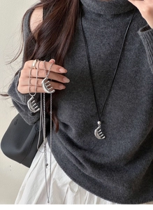 Detail showing avant-garde silver comb pendant on sleek metal chain and black rope cord