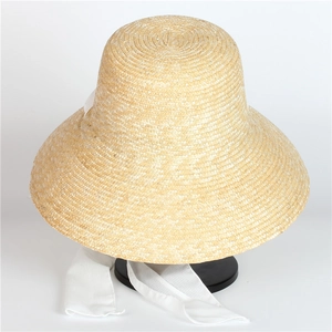 Minimalist straw sun hat with wide brim and white ribbon tie on a black stand