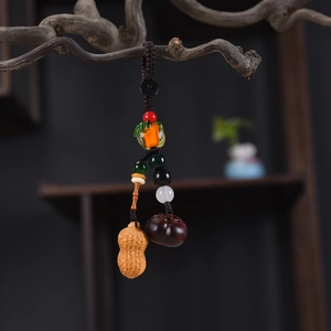 Macro detail of sandalwood peanut and persimmon pendants on a vintage wooden branch