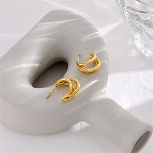 Three-layered gold titanium steel hoop earrings on minimalist ceramic pedestal