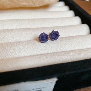 Gros plan de boucles d'oreilles roses en résine violette sur présentoir en velours