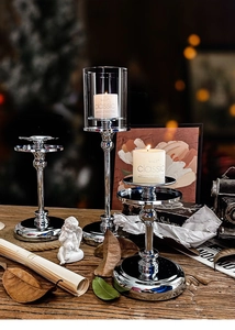 Detailed view of silver metal candle holders with glass shade on a dark wooden table