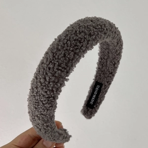 Detailweergave van de pluizige grijze fleecestof en het handgemaakte label op de hoofdband