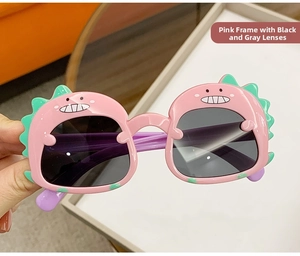 Close-up of pink dinosaur sunglasses with green fins and cartoon teeth patterns