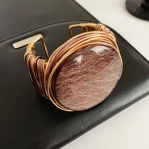 Close-up of vintage resin bangle featuring intricate hand-wrapped golden wire details