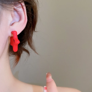 Close-up of a minimalist burgundy star-shaped earring on model ear for display