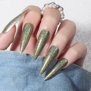 Detailed view of long stiletto press-on nails with holographic gold and green laser glitter