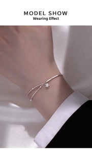 Detail of silver star charm bracelet on wrist with elegant silk and fabric backdrop