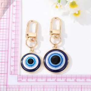 Blue Evil Eye resin keychain pendants with gold metal hooks shown next to a ruler