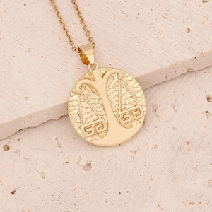 Macro view of Libra zodiac gold pendant necklace on textured beige stone surface