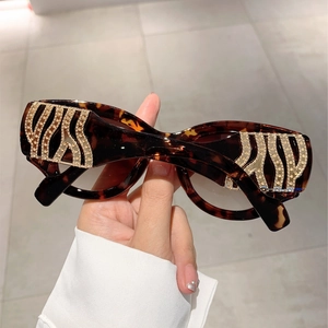 Detail of tortoiseshell sunglasses featuring gold zebra pattern temples with rhinestones