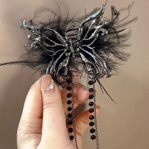Detail of silver liquid metal butterfly hair claw with black feathers and beaded tassels