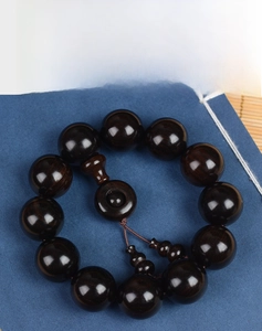 Macro shot of polished ebony wood beads bracelet with natural dark grain and smooth finish