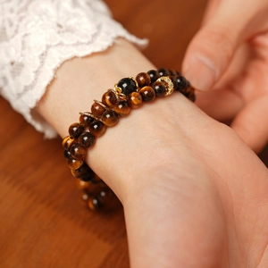 Close-up of tiger eye stone beaded bracelet with gold accents on a female wrist