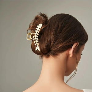 Eleganter goldener Fischgräten-Haarclip für Damen, getragen an einer Dutt-Frisur