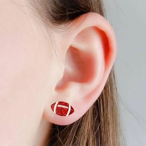 Boucles d'oreilles football à paillettes rouges portées sur l'oreille d'un mannequin