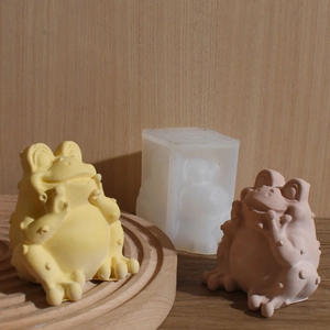Detail view of frog silicone mold with yellow and pink frog resin figures on wood surface