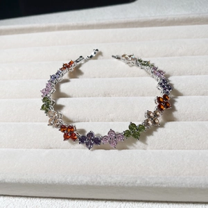 Macro shot of silver clover bracelet with colorful teardrop cubic zirconia on a velvet tray