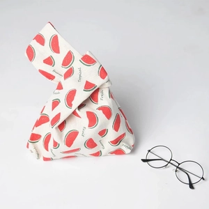 Detail of linen knot bag with fresh watermelon print and glasses for size reference