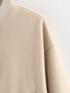 Detailed close-up of ribbed knit collar and high-quality beige wool tweed jacket seams