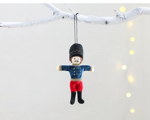 Classic blue and red fabric nutcracker soldier ornament hanging on a festive branch