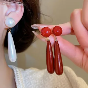Elegant silver needle drop earrings with glossy white and vintage red pearl pendants