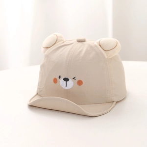 Detailed embroidery of a cute bear face on a cream baby sun hat with plush ears