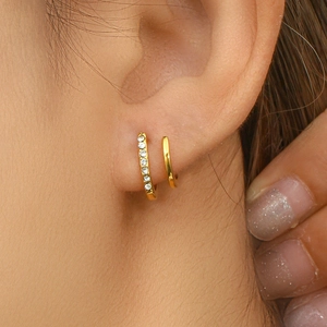 Close-up of golden double-layered hoop earrings with white zircon inlay on model ear