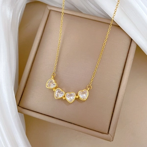 Detail of gold clover heart pendant with sparkling crystals on white silk background
