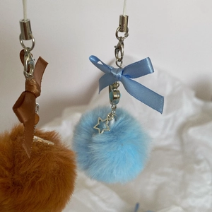 Detailed view of soft plush ball charms with silk bows and silver star pendants