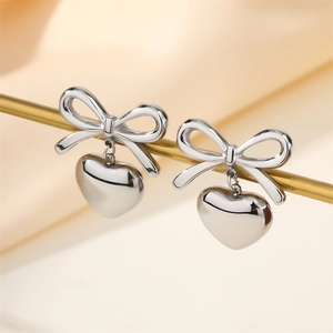 Silver stainless steel bow earrings with heart pendants on a professional display