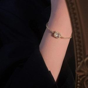 Detailed view of a gold tennis bracelet with a square zircon centerpiece on a wrist