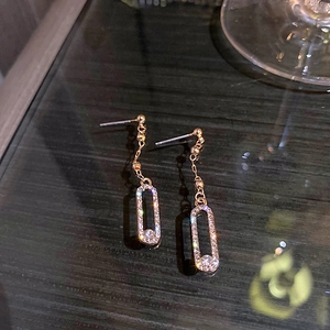 Close-up of gold geometric oval earrings with sparkling cubic zirconia on a dark surface