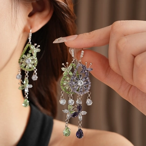 Close-up of floral cubic zirconia earrings with green water drop charms on a model