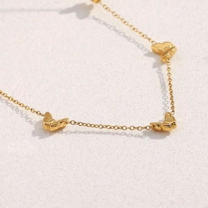 Makroaufnahme der vergoldeten Schmetterlingshalskette mit 18K Goldkette auf weißem Grund