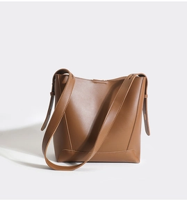 Detailed close-up of brown leather bucket bag featuring minimalist design and wide strap