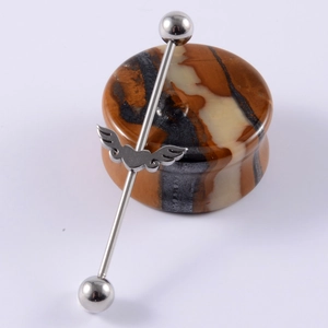 Silver industrial piercing bar featuring a detailed winged heart design with smooth steel beads