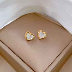 Macro detail of heart stud earrings with golden beaded edges and white shell inlay