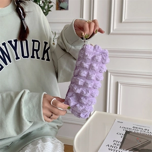 Detail of purple bubble texture fabric on a soft storage pouch held by a model
